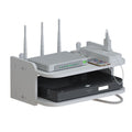 A white multi-port router and power strip shelf organizer holding a router with four antennas, a power strip, a smartphone, and a black DVD player, shown on a white background.