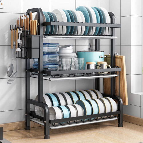 3 tier dish drying rack in a kitchen holding plates, storage containers, cups and cutting boards