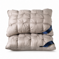 Two tufted rectangular pillows stacked on a white background, in a light taupe-beige color with a dark blue and gold accent ribbon on the right side.