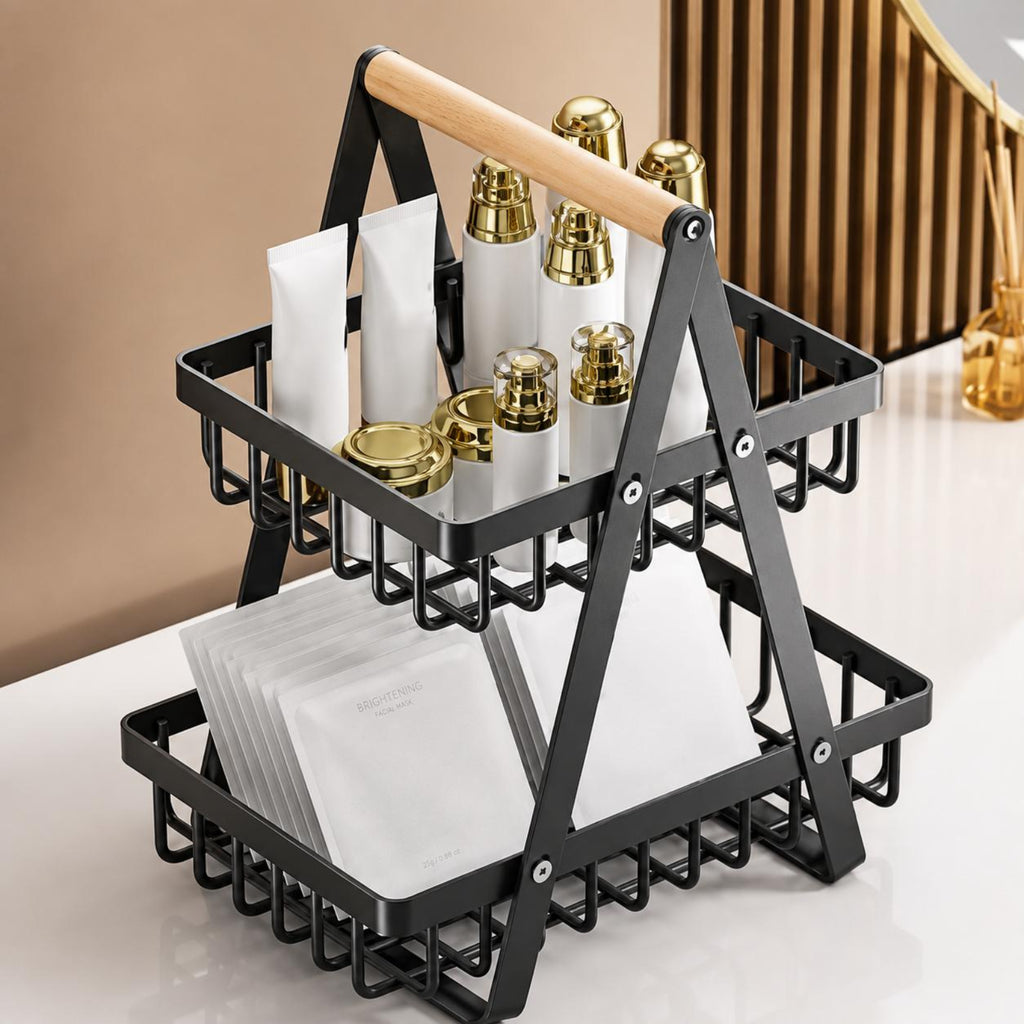 A two-tier black metal cosmetic organizer with a light wood handle, shown holding skincare bottles and packets on a white surface in a styled indoor setting.